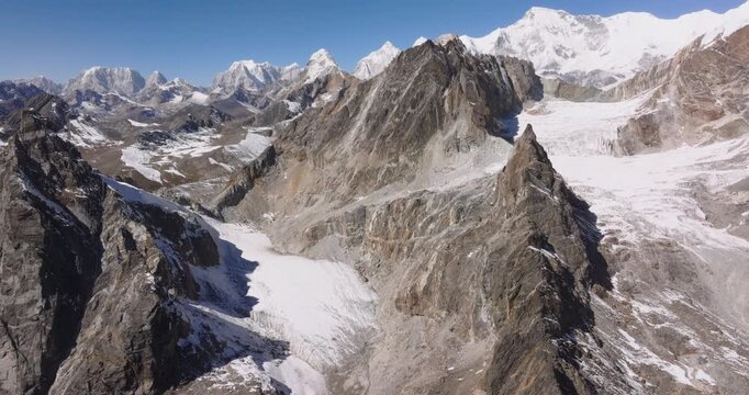 Chola Pass Everest region Nepal, aerial drone hovering over rugged alpine rock ridges with patches of snow and steep mountain slope
