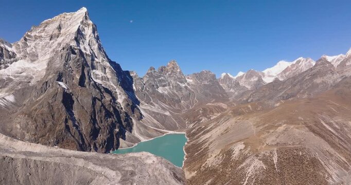 Chola Tshe Lake Everest Nepal, drone slowly orbiting the turquoise glacial waters of Chola Tshe lake nestled beneath the massive rock wall of Cholatse peak.