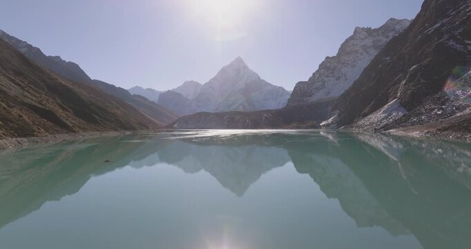 Chola Tshe Lake Nepal, aerial pull out shot over calm turquoise waters revealing the striking reflection and silhouette of Ama Dablam mountain in the Everest region.