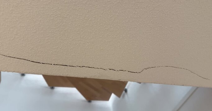 Close-up of a long crack in an interior wall above a staircase. Concept of structural damage, building defects, home inspection, construction issues, renovation, and property maintenance.