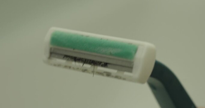 Extreme macro view of a used razor blade with trapped hair after shaving. Concept of personal hygiene, grooming, beard care, shaving routine, and cleanliness.
