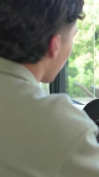 Vertical video: Reaching, man in green sweater donning headset at desk, starting recording near mic