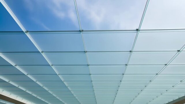 Symmetrical frosted glass ceiling panels in metal grid seen from low angle, with diffuse overhead glow, circular fasteners, repeating squares, clean geometric interior design
