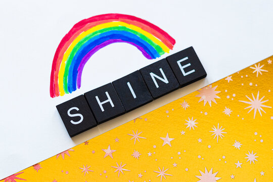 Black and White Shine Text Under a Rainbow on a Golden Starry Background
