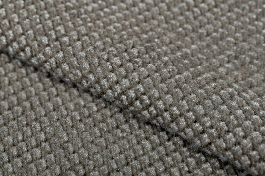 Charcoal grey woven chenille fabric texture background with diagonal seam folds