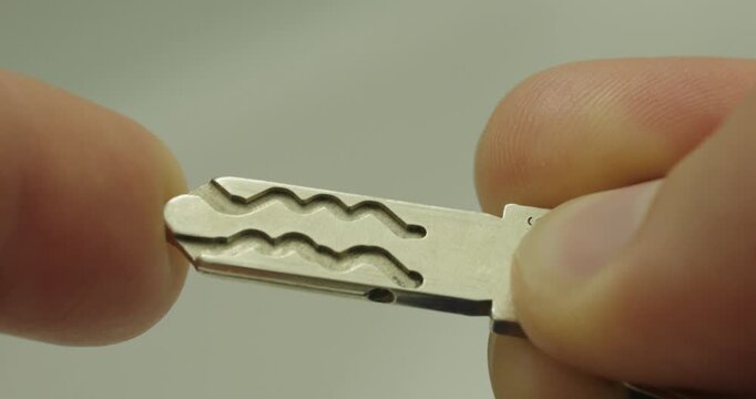 Extreme macro view of a metal security key held between fingers. Concept of access control, home security, locking systems, property protection, and everyday household objects.