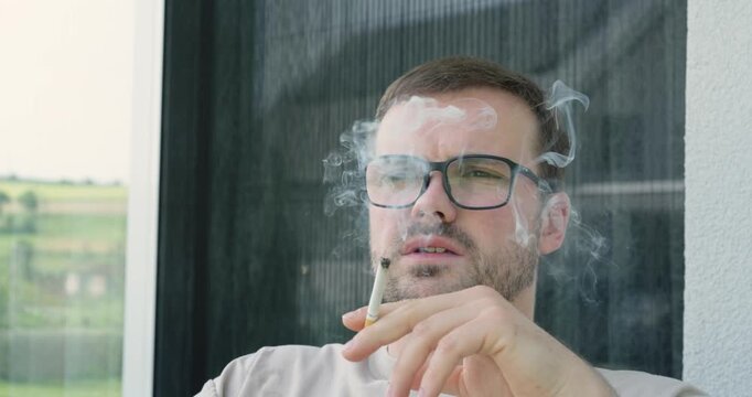 Man smoking a cigarette outdoors with visible smoke. Concept of tobacco use, nicotine addiction, unhealthy lifestyle, and smoking habits.