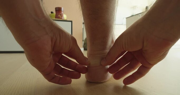 Close-up of a person applying an adhesive bandage to the heel of the foot. Concept of first aid, blister prevention, foot care,foot protection, and personal healthcare.