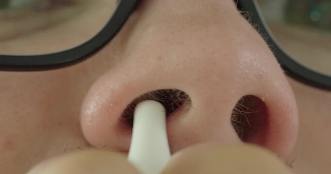 Extreme macro close-up of a person applying nasal spray into a nostril. Concept of nasal care, allergy relief, congestion treatment, respiratory health, medication, and personal healthcare.