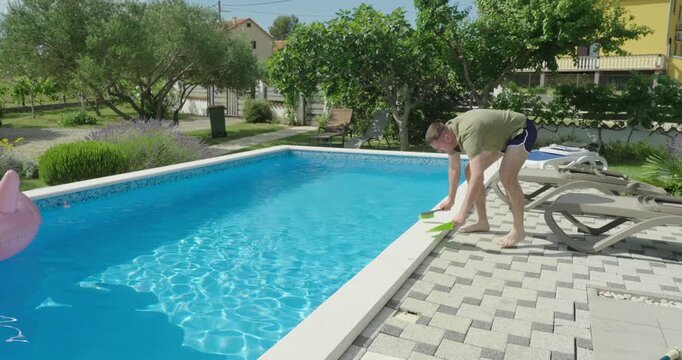 A man cleaning the area around a swimming pool, focusing on tidying the poolside environment. Highlights maintenance, hygiene, and outdoor facility care.