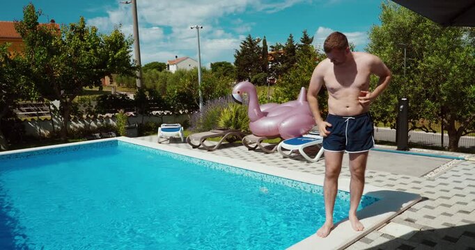 A man standing beside a swimming pool showing skin discomfort and scratching his body after swimming. Focus on possible irritation from pool water and sensitivity to chemicals in a resort environment.