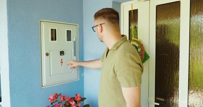 Man inspecting a residential electrical panel outside a house.