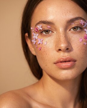 Woman Beauty Portrait with Pink Flowers Placed on Freckled Face
