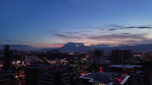 Vista de altura de Ciudad de Guatemala con rascacielos residenciales y luces urbanas de noche. Atardecer dram&aacute;tico y colorido sobre el horizonte de la Ciudad de Guatemala.