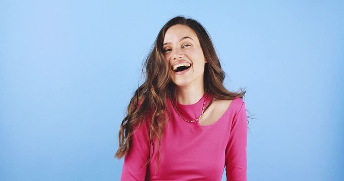 Young woman waving her hand and gesturing come here, laughing and smiling with joy, friendly and inviting expression studio isolated on blue background, concept of welcome, communication, and greeting