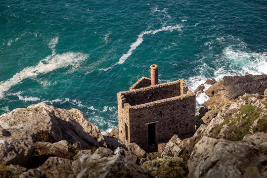 Historic stone engine house of Botallack Mine perched on rugged cliffs overlooking the turquoise sea in Cornwall