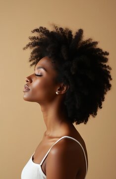 Black woman with natural afro hair. Side profile shows closed eyes peaceful facial expression. Beauty shot highlights skin glow and curls. Inner peace and self-care theme.