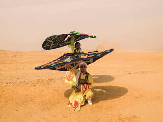 Fototapeta premium Vibrant Tanoura folk dancers spinning colorful skirts overhead in the desert before the Giza pyramids in Egypt ideal for cultural tourism and festival