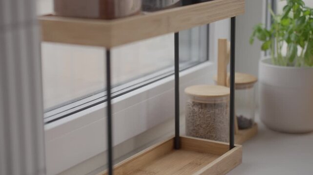 Hand takes salt and sugar jars from kitchen organizer near window. Concept of home cooking and food preparation