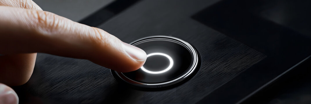 Close-up of finger pressing illuminated touch button on modern black device surface