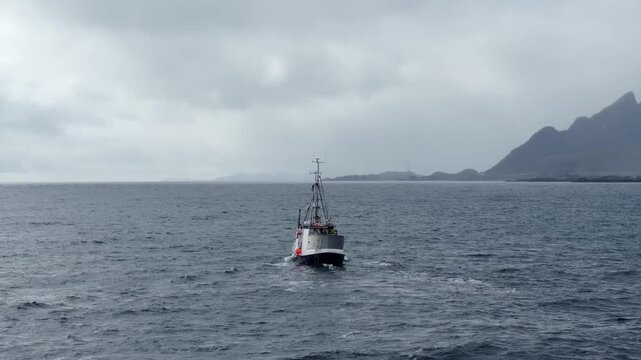 Small fishing boat on choppy sea near rugged coastline under overcast sky