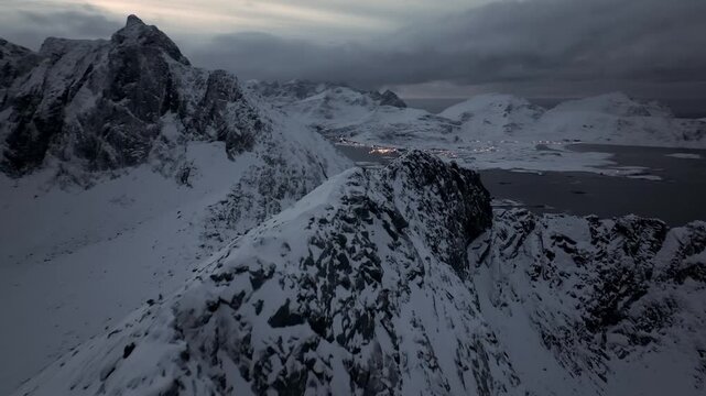 Aerial dusk view of snow-covered rocky coastal ridge and fjord