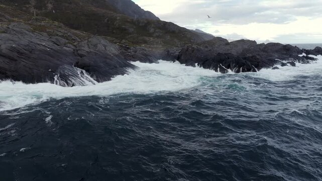 Rugged rocky headland with crashing surf under overcast sky