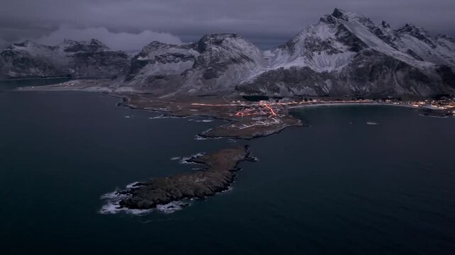 Aerial night view of snow dusted coastal village on a narrow peninsula