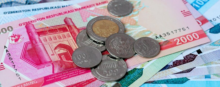 Uzbekistani som money bills and coins on table. Uzbekistan cash of UZS currency close up