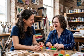 Fototapeta premium Two women smiling while playing with colorful wooden blocks