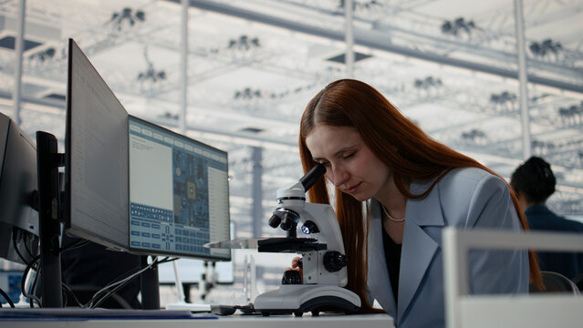Studying microchip architecture, microscope and woman in microelectronics development facility, researching semiconductor materials, camera A close up.
