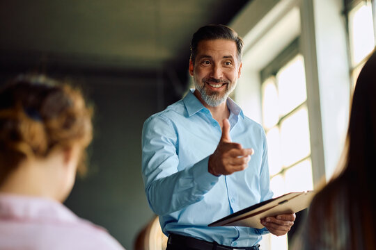 Happy business leader talking to his team during meeting in office.