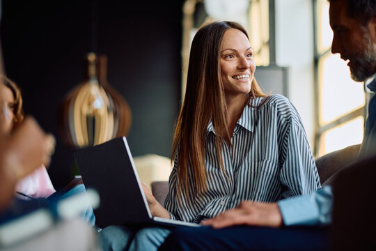 Happy businesswoman cooperating with colleague while working on computer in office.