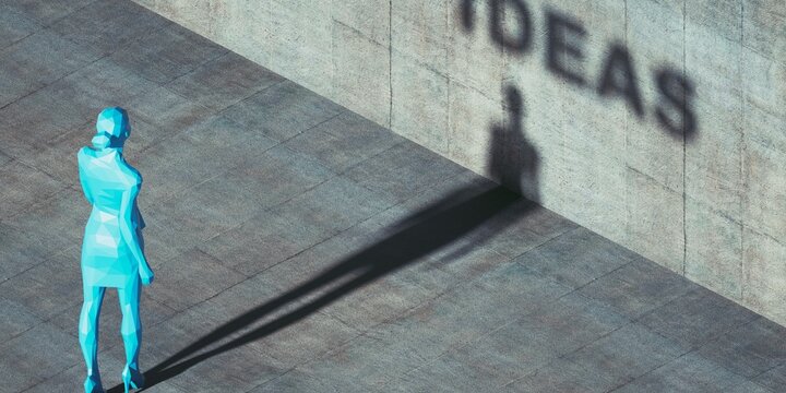 Businesswoman casting a shadow that forms the word ideas on a wall