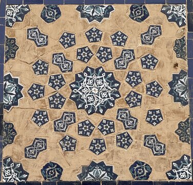 Close-up of a traditional Islamic geometric mosaic tile panel serving as a textured background, featuring an intricate radial girih pattern with a central dark blue ten-pointed star and pentagon inlay