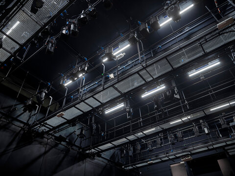 Overhead theater lighting rig with trusses, spotlights and rigging against a dark ceiling, a professional stage technical installation
