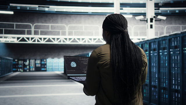 Data center engineer uses laptop in a data center to upgrade server hardware and improve workload capacity.