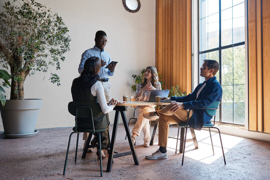 Diverse business professionals collaborating around a table. Actively listening and contributing during an informal meeting. Discussing ideas and strategies for project development