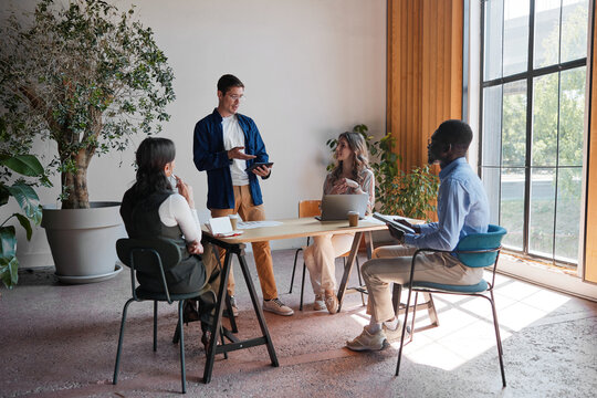 Business professional leading a presentation to a diverse team of colleagues, engaging in a collaborative discussion and sharing innovative ideas in a bright contemporary meeting room