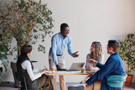 Diverse business professionals having informal startup meeting, collaborating and brainstorming creative ideas for success in modern office environment