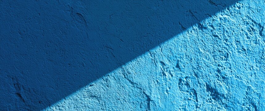 Textured blue wall with a diagonal shadow cutting across it
