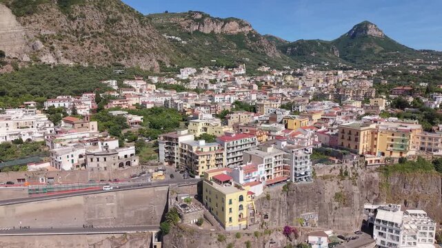 Aerial view of Meta di Sorrento colorful buildings with dramatic rocky mountains, lush vegetation, and tuff cliffs, Sorrento Peninsula, Naples, Italy