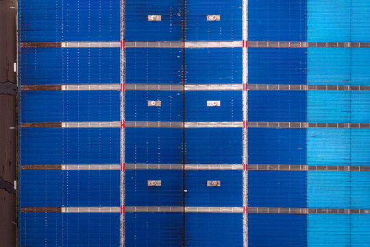 Aerial view of the blue corrugated metal roof of the Tecnovia Acores industrial facility with ventilation units and structural grid lines in Rabo de Peixe, Acores, Portugal.