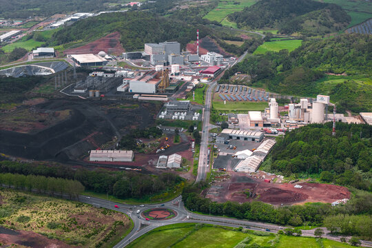 Aerial view of the Tecnovia Acores industrial facility with processing plants, storage warehouses, and a road network in the rural landscape of Rabo de Peixe, Acores, Portugal.