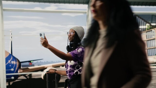 Happy couple walking in airport taking selfies with smartphone, capturing positive travel moment, for relaxed airport waiting and travel lifestyle concepts.