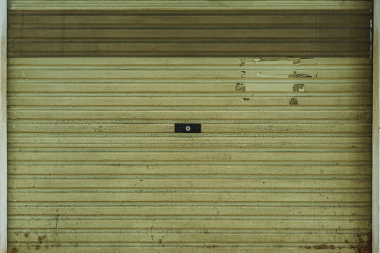 Old weathered metal rolling shutter door of a closed shop