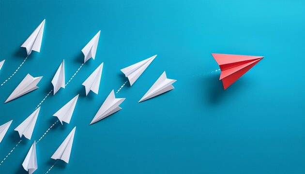 paper planes in a row on blue background and one paper glider going in different direction breaking new ground and stepping out of the line concept