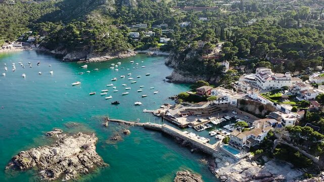 Aerial view of Aiguablava Beach, one of the most beautiful coves on the Costa Brava, featuring crystal-clear turquoise waters, rocky islets and lush Mediterranean pine forests. 