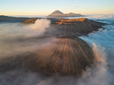 Aerial view of Bromo Tengger Semeru National Park featuring volcanic craters rising above a sea of clouds at sunrise in Probolinggo, East Java, Indonesia.