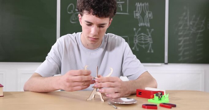 Student assembling solar concentrator model during physics lesson in classroom, camera moving in and out